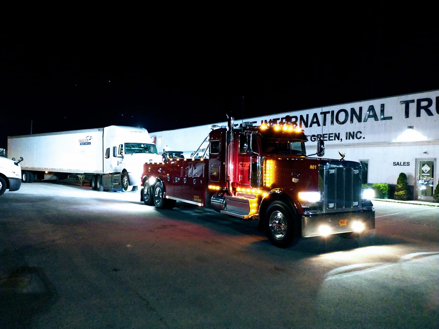 red tow truck pulling semi truck