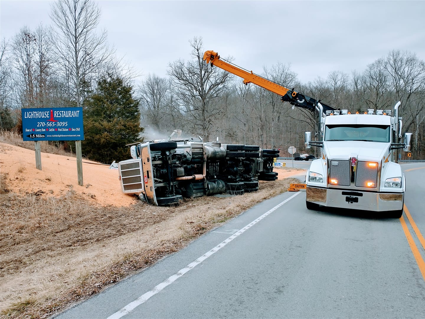 crane tow truck lifting flipped over semi truck